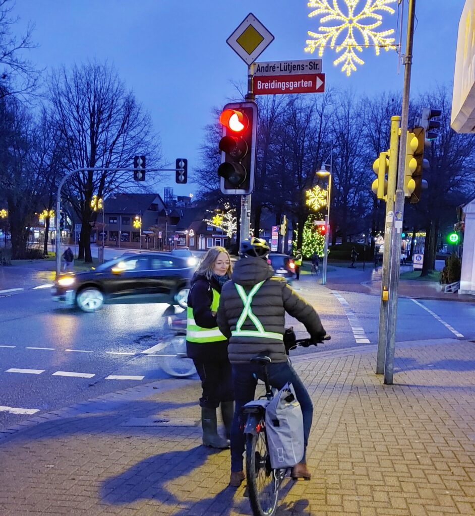 Eine Frau spricht mit einem Radfahrer an einer Ampel.